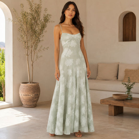 Woman in a light green floral dress standing in a sunlit room with a couch and plants.