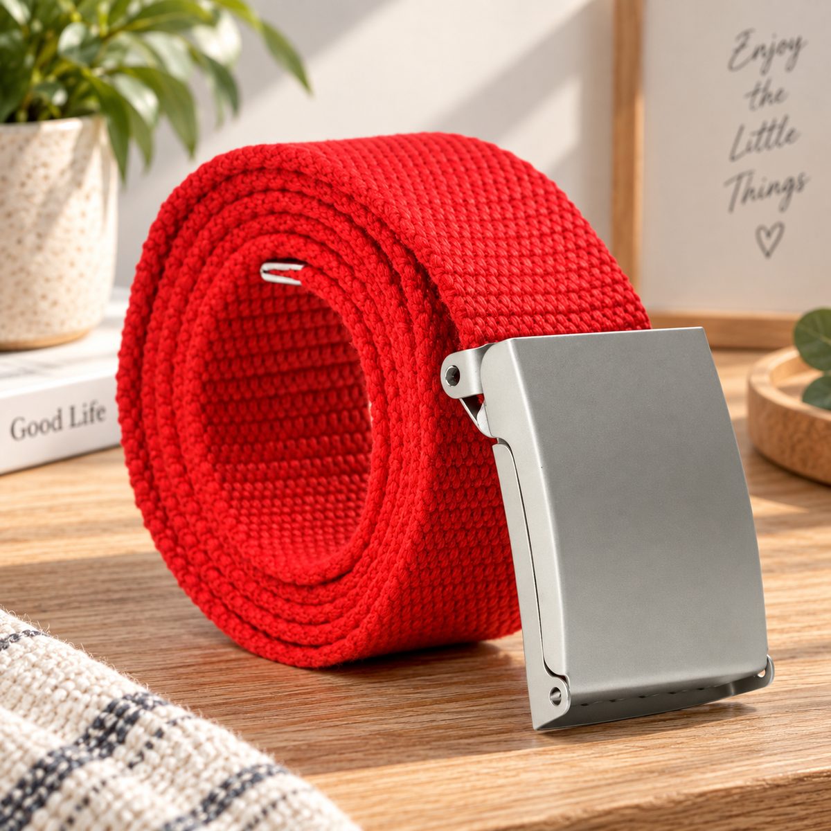 Red woven belt arranged in a coil with its silver buckle facing forward.