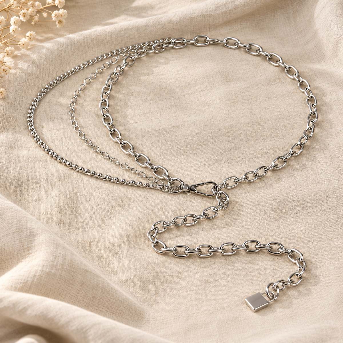 Silver Siren’s Sparkle multilayer chain belt arranged on soft beige linen.